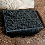 A black plastic cube inserted into the ground to assist in water infiltration.