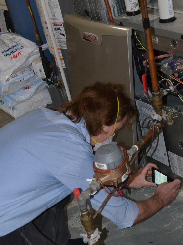 A man doing a home energy audit records the rating of a furnace during the assessment.